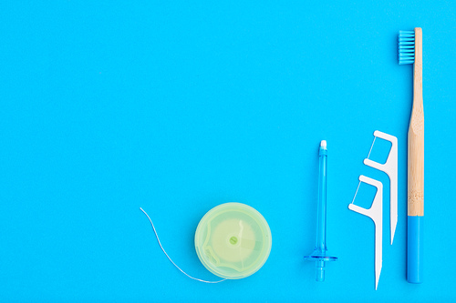 Toothbrushes and oral care tools over blue background top view copy space flat lay. Tooth care, dental hygiene and health concept.