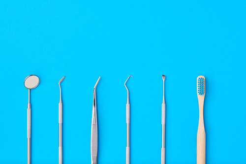 Dentist tools over blue background top view copy space flat lay. Tooth care, dental hygiene and health concept.