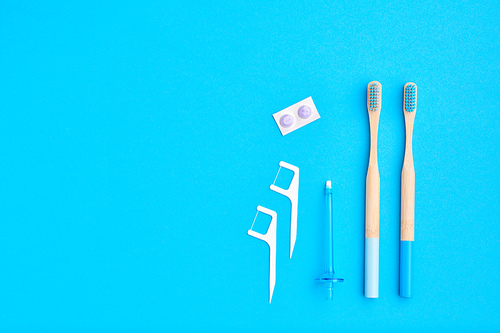 Toothbrushes and oral care tools over blue background top view copy space flat lay. Tooth care, dental hygiene and health concept.