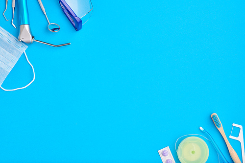 Dentist tools over blue background top view copy space flat lay. Tooth care, dental hygiene and health concept.