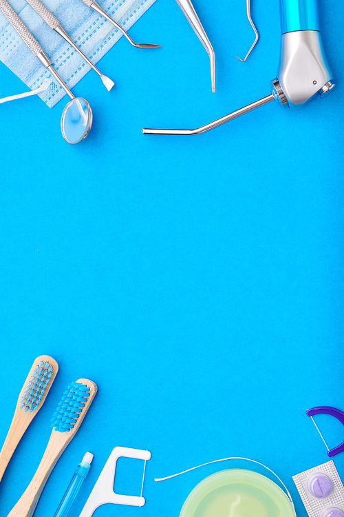 Dentist tools over blue background top view copy space flat lay. Tooth care, dental hygiene and health concept.