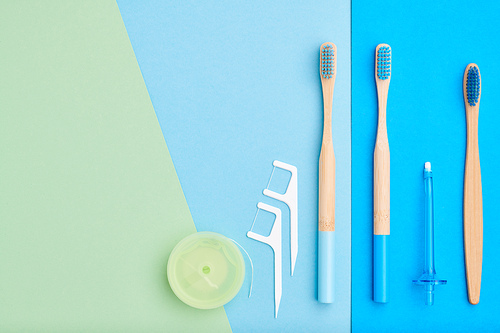 Toothbrushes and oral care tools over blue background top view copy space flat lay. Tooth care, dental hygiene and health concept.