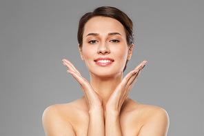 beauty, bodycare and people concept - beautiful young woman with bare shoulder over grey background