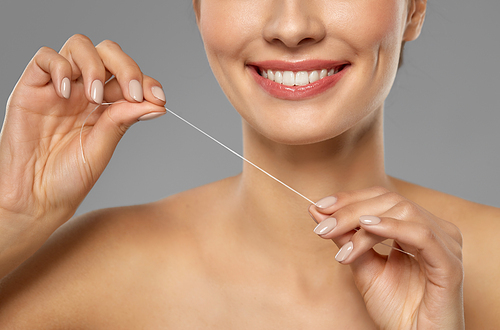 oral hygiene, dental care and health concept - close up of smiling young woman with floss cleaning teeth