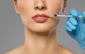 cosmetology, plastic surgery and beauty concept - beautiful young woman and hand with syringe making lifting injection over grey background and snow