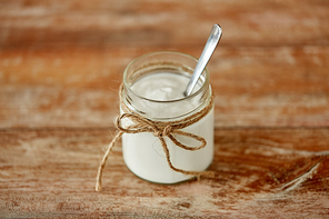 food and dairy products concept - close up of homemade yogurt or sour cream in vintage glass jar on wooden table