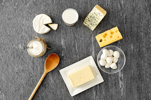 food and eating concept - different kinds of cheese, milk, yogurt and butter on stone table