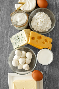 food and eating concept - close up of cottage cheese, bottle of milk, homemade yogurt with butter and chicken eggs on stone table