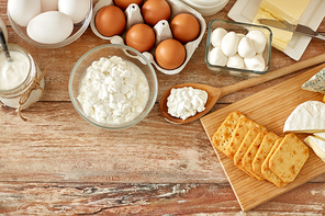 food and eating concept - close up of cottage cheese, crackers, yogurt with butter and chicken eggs on wooden table