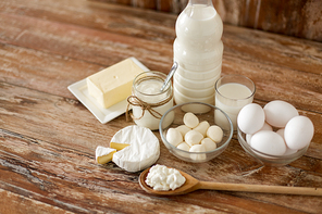 food and eating concept - close up of cottage cheese, bottle of milk, homemade yogurt with butter and chicken eggs on wooden table