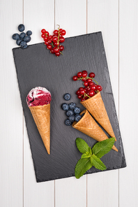 Red fruits ice cream cone on wooden table.