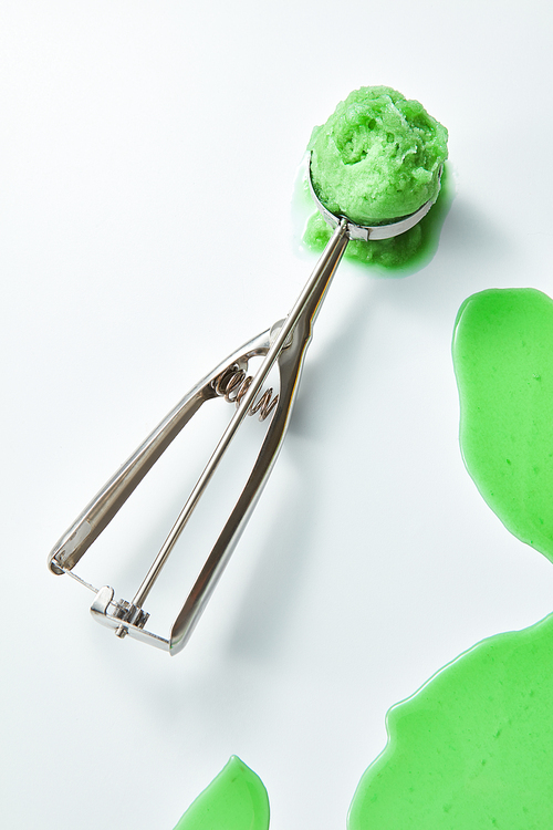 Scoop home made ice cream. Greens melting ice cream with a pattern of splashes on a gray background with a copy of the space for text. Cold summer dessert. Top view