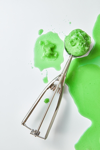 Fruit melting ice cream in a metal scoop with splashes and drops on a gray background, copy space for text. Flat lay