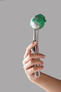 Homemade mint ice cream in a scoop, a girl's hand holds on a gray background a copy of the space for text