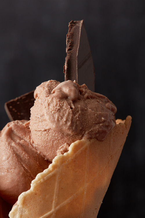 Chocolate ice cream with pieces of chocolate in a waffle cone close up