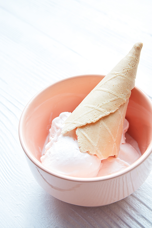 Vanilla ice cream in a plate with a waffle cone close-up isolated on a white background