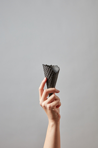 A woman's hand holds a crisp empty black waffle cone on a dark gray background with copy space for your business ideas