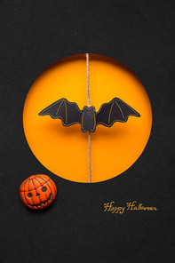 Creative halloween concept photo of a bat made of paper on orange black background.