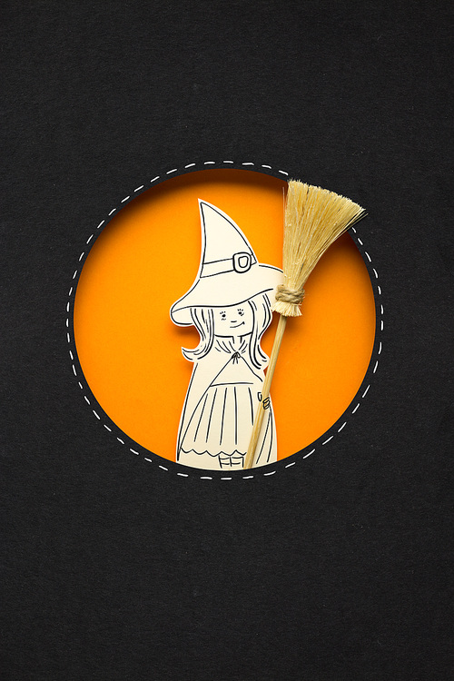 Creative halloween concept photo of witch with broom made of paper on black orange background.