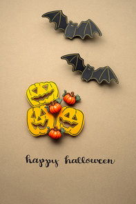 Creative halloween concept photo of pumpkins and bats made of paper on brown background.