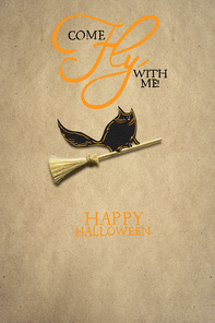 Creative halloween concept photo of a cat on a broom made of paper on brown background.