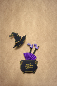 Creative halloween concept photo of witch in a boiler made of paper on brown background.