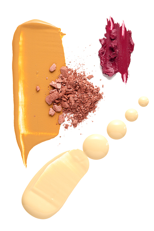 Creative concept photo of cosmetics swatches beauty products foundation cream with lipstick and eyeshadow on white background.
