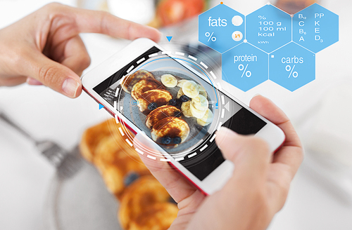 food , eating and technology concept - hands with pancakes on smartphone screen over nutritional value chart
