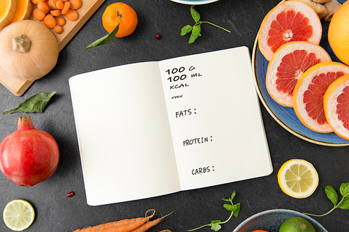 healthy eating, food and diet concept - close up of notebook, fruits and vegetables on slate table top