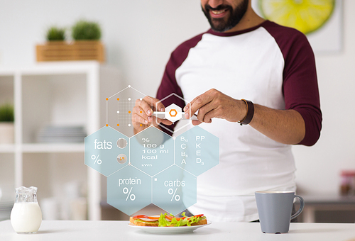 food, healthy eating and people concept - close up of man with smartphone having sandwiches for breakfast at home kitchen over nutritional value chart