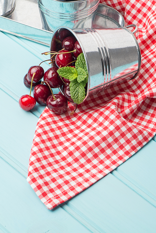 Ripe red cherries in blue wooden table background.