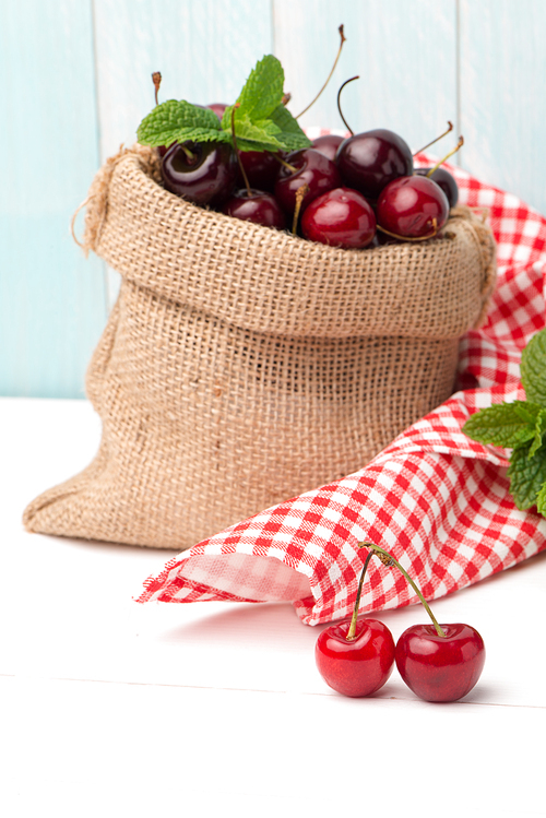 Cherries in small bag on the wooden table.
