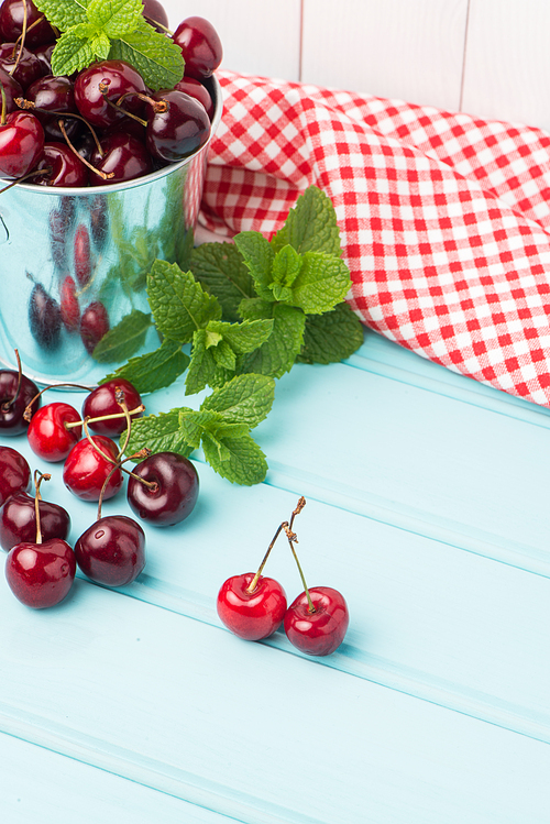 Ripe red cherries in blue wooden table background.