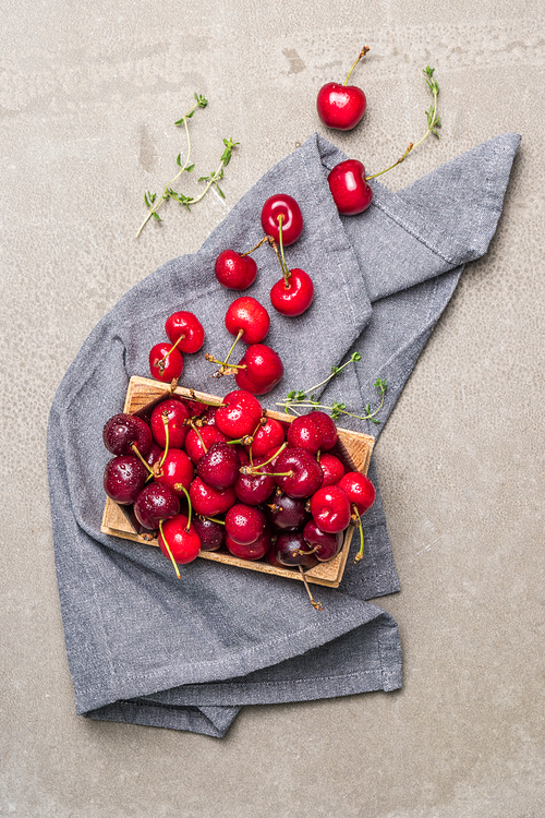 Red ripe cherries in small wooden box on kitchen countertop.