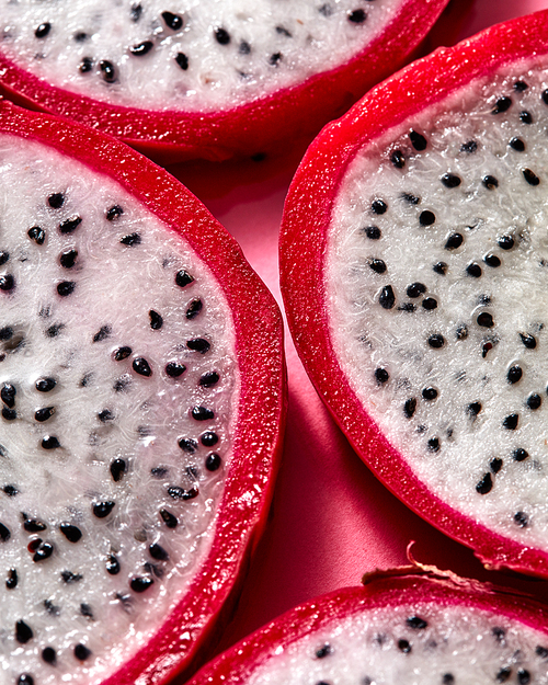 Top view of tropical exotic cut round slices of Dragon fruit or Pitaya on a pink background. Close-up view.