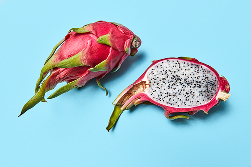 A ripe fruit pitahaya a whole and a half on a blue background with space for text.