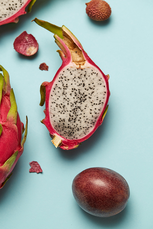 Exotic pink dragon fruit half on blue background with passion fruit. Sweet tropical fruit, juicy pitaya cut