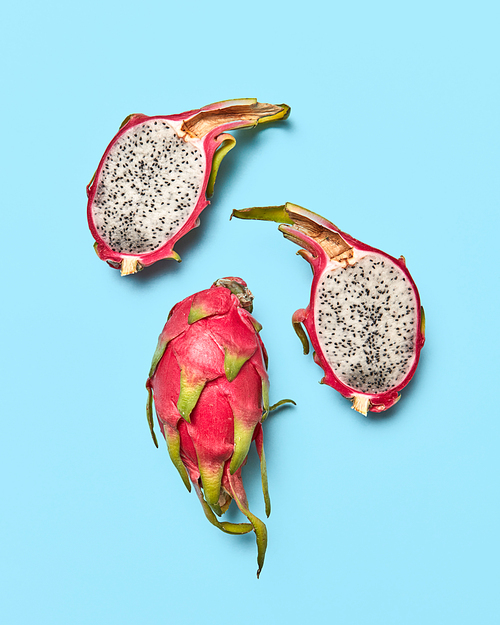 Exotic juicy fruit pitahaya. Whole and halved fruit on a blue background with space for text. Healthy food. Flat lay