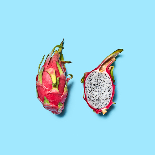 Ripe whole and juicy half fruit of pitahaya on a blue background with space for text. Flat lay