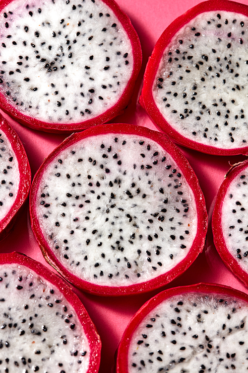 Top view of tropical exotic cut round slices of Dragon fruit or Pitaya on a pink background. Close-up view.