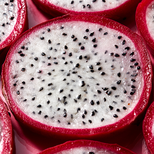 Top view of tropical exotic cut round slices of Dragon fruit or Pitaya on a pink background. Close-up view.