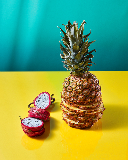 The composition with tropical exotic fruit single pineapple and dragon fruit, pitaya made up of slices on a duotone yellow-green background.