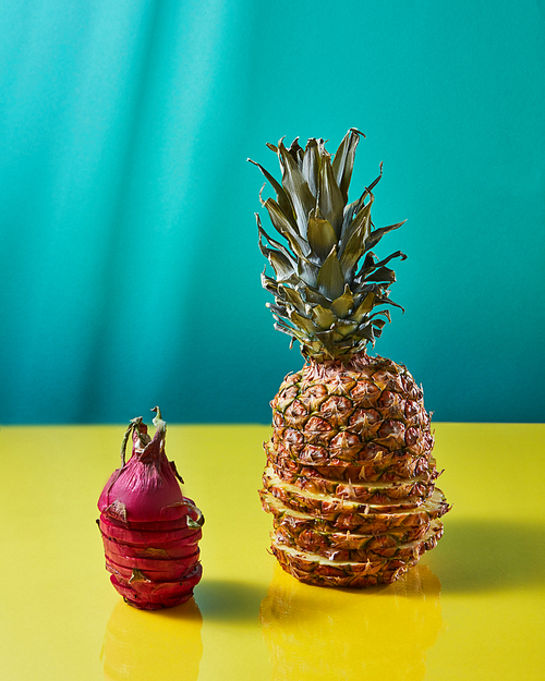 The composition with tropical exotic fruit single pineapple and dragon fruit, pitaya made up of slices on a duotone yellow-green background.