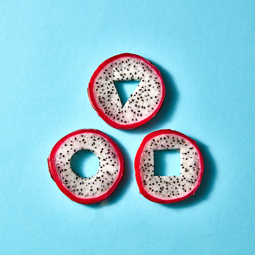 Different geometric shapes made from pitaya represented on a blue paper background. Flat lay