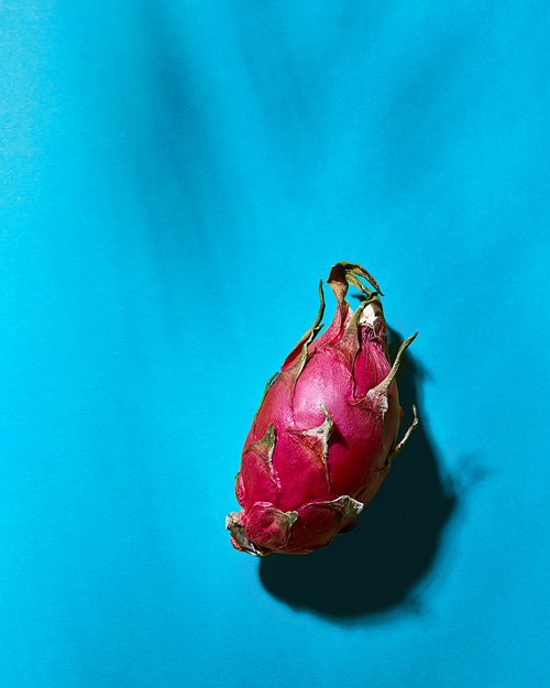 Healthy dragon fruits close up and deep shadows on a blue background with copy space, flat lay