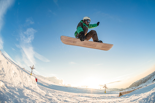 Snowboarder executing a radical jump against sunset sky.