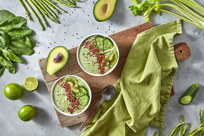 Vegetable smoothies from avocado, asparagus, spinach, cucumber and kiwi with flax seeds on a wooden board on a gray kitchen table. Dietary organic food.