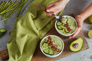 green seed flaxseeds pudding bowl in the female hands on cute wooden board with asparagus and avocado. Food or Healthy diet concepton a stone background. Flat lay