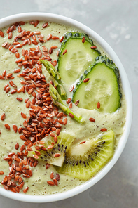 Vegetarian healthy smoothies from green organic vegetables with flax seeds in a white bowl on a grey background, table. Top view