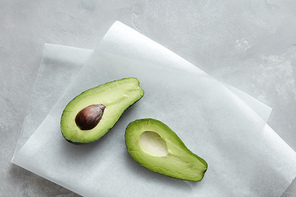 Fresh Avocado sliced on paper on a gray stone background .